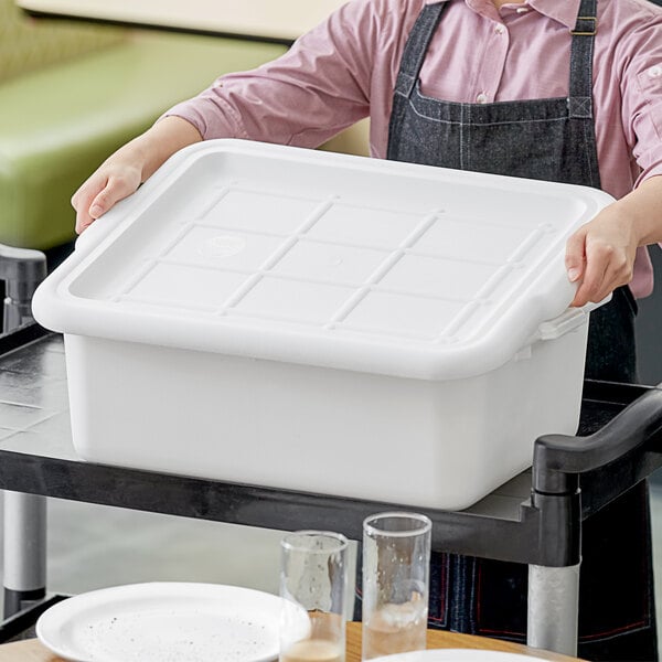 A person holding a white plastic container with a lid.