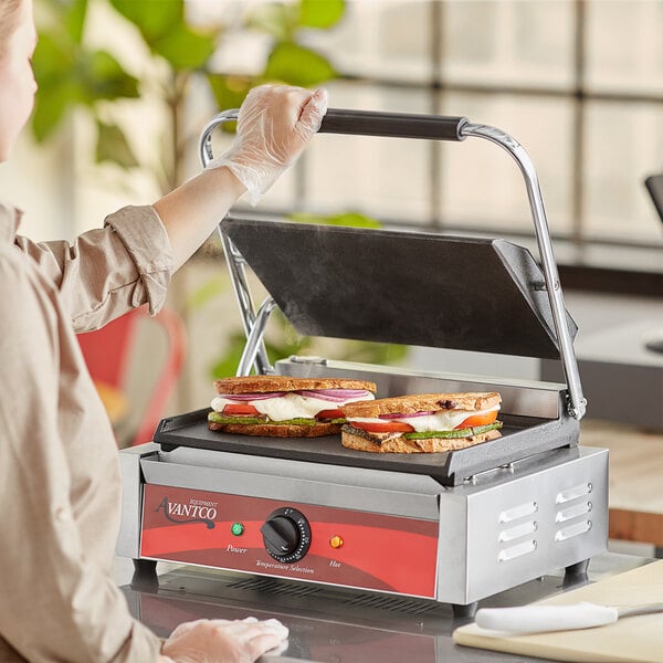 A woman cooking sandwiches on an Avantco commercial panini grill.