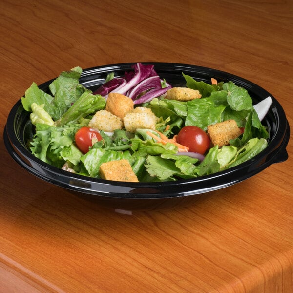 A salad in a black bowl on a table.
