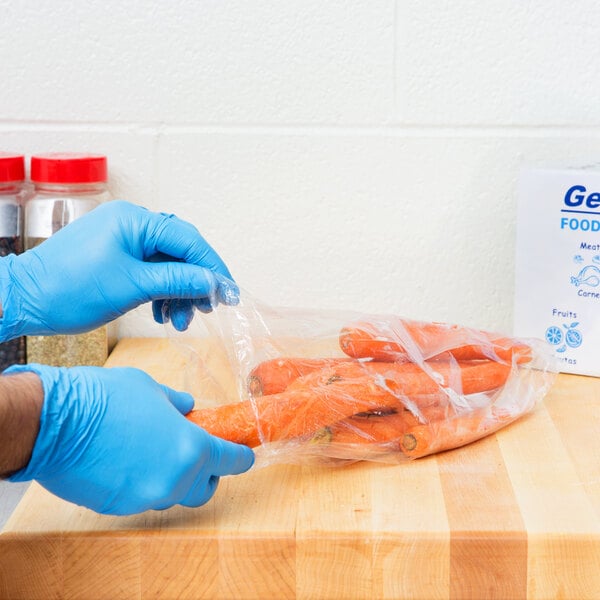 A person in blue gloves holding a plastic bag of carrots.