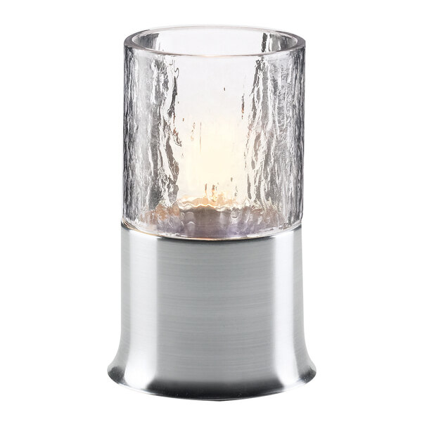 A Sterno brushed silver lamp base with a lit candle in a glass holder.