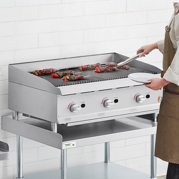 A woman cooking food on a Cooking Performance Group gas countertop charbroiler.