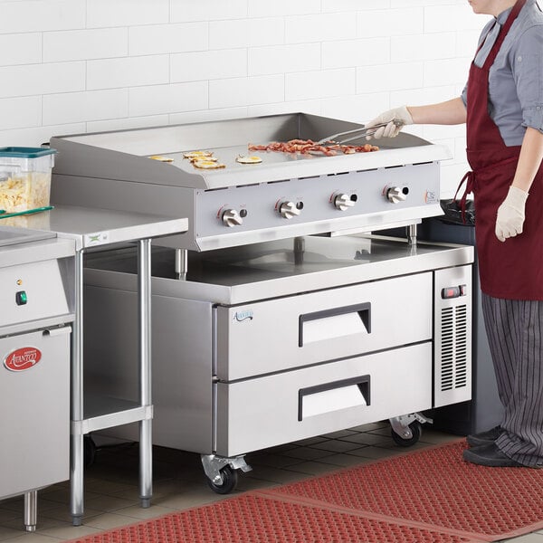 A woman cooking food on a Cooking Performance Group countertop gas griddle in a commercial kitchen.