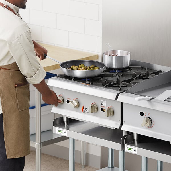 A man cooking food on a Cooking Performance Group countertop gas range.