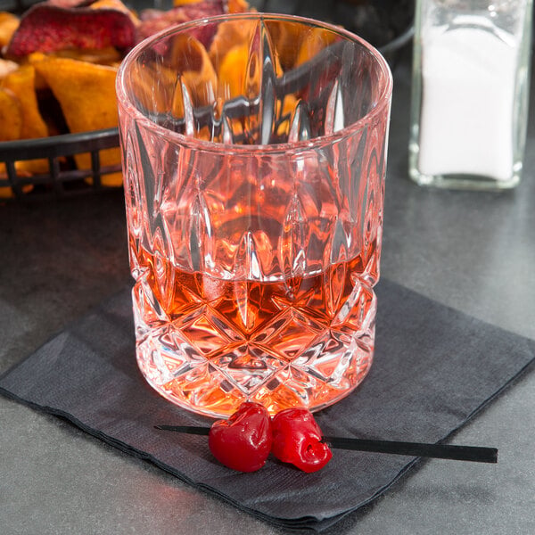 A Nachtmann Noblesse rocks glass filled with a pink drink and cherries on a napkin.