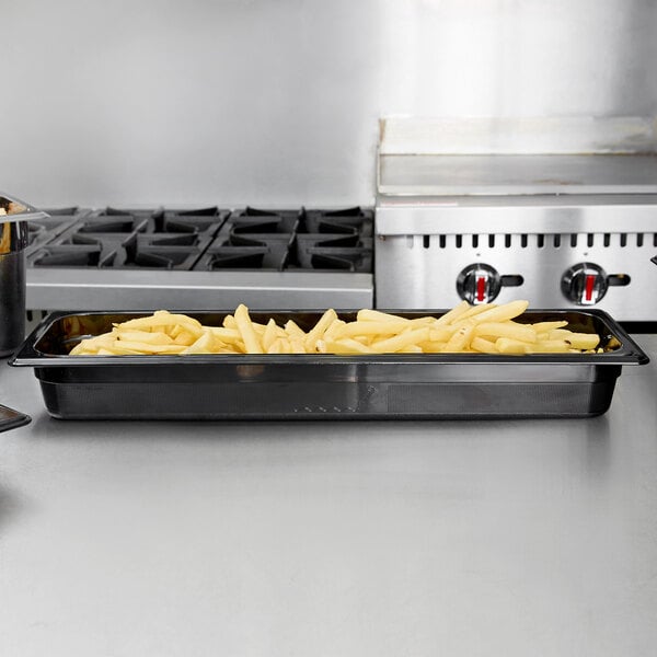 A black Rubbermaid plastic food pan with french fries on a counter.