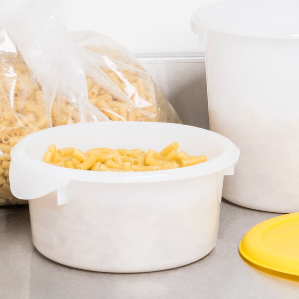 A Rubbermaid white plastic food storage container filled with pasta with a yellow lid.