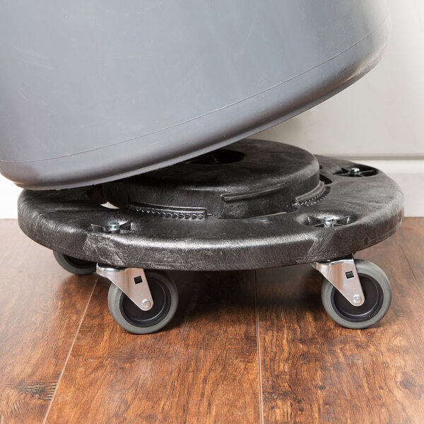 A black Rubbermaid dolly with a grey drum on it.