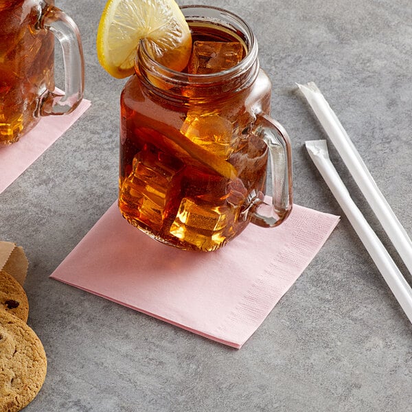 A glass mug with ice and a lemon slice on top with a Choice Pink 2-Ply Customizable Beverage Napkin.