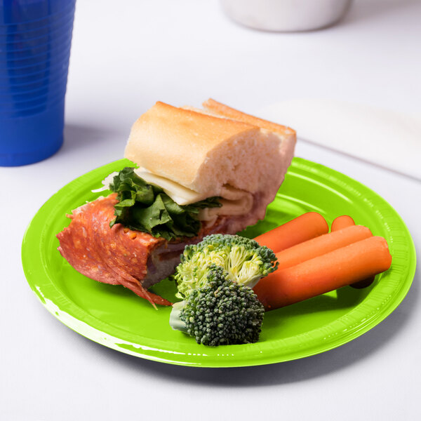 A sandwich with lettuce, cheese, and broccoli on a Fresh Lime green plastic plate.