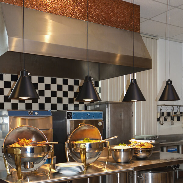 A ceiling mount Hanson Heat Lamp with a black finish heating a large metal container of food in a commercial kitchen.