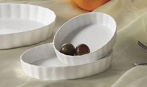 A white oval CAC serving dish with grapes inside.