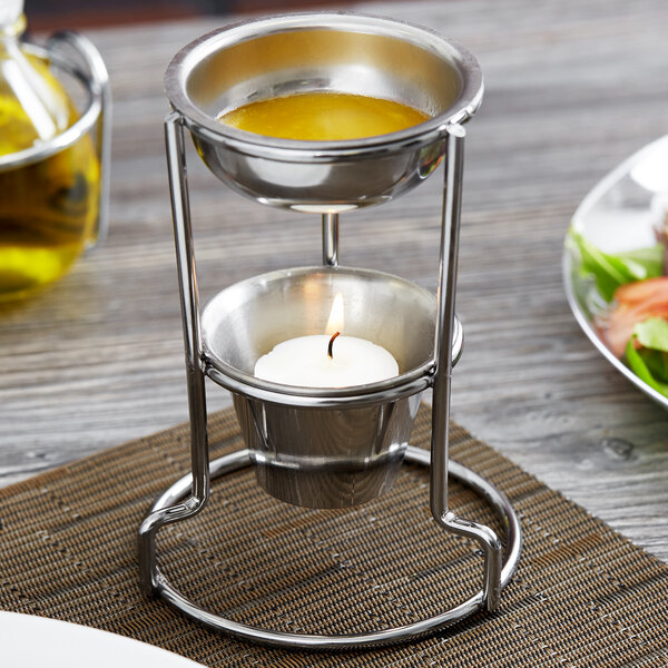 A Vollrath butter melter with a lit candle on a table.