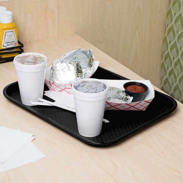 A black fast food tray with two cups of coffee and a drink on a table.