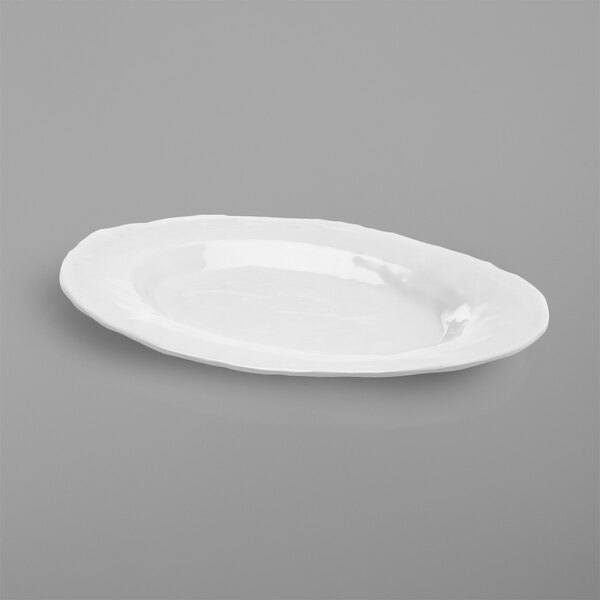 An Elite Global Solutions Tuscany white oval melamine platter on a gray surface.