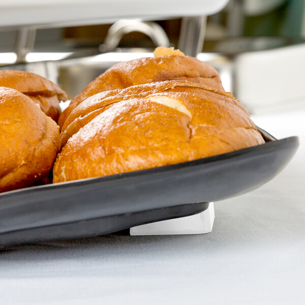 Elite Global Solutions white wedge display with bread on a white tray.