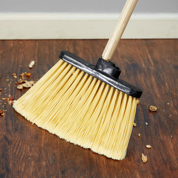 A Carlisle Duo Sweep broom head with flagged bristles on a wood floor.