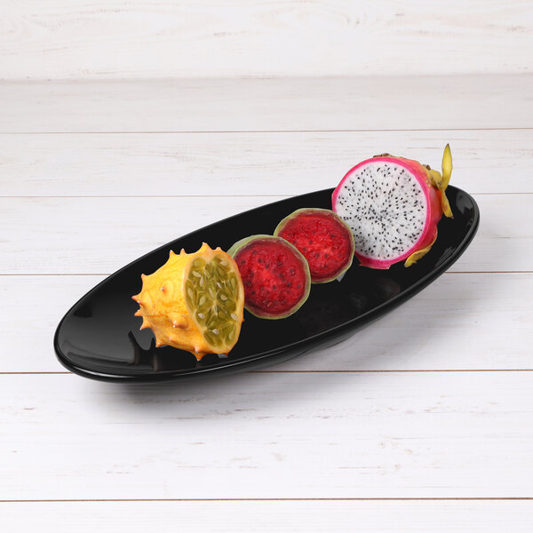 An Elite Global Solutions black oblong platter with dragon fruit, passion fruit, and lychee.