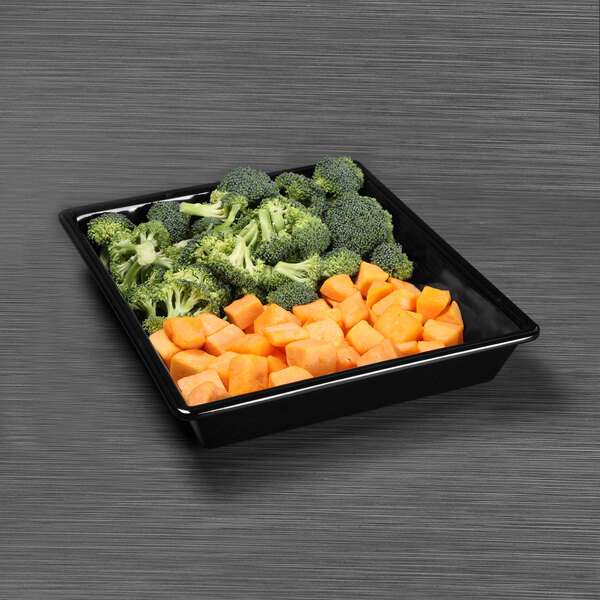 A black rectangular melamine bowl with broccoli and sweet potatoes on it.