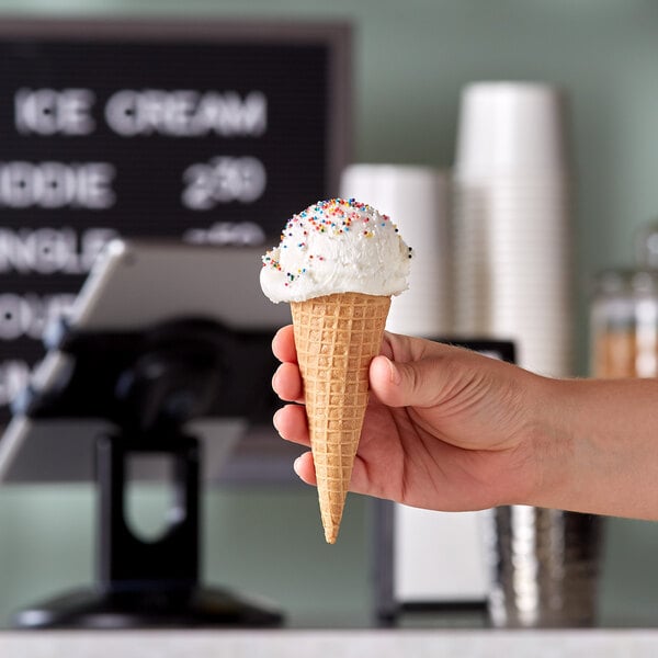 A hand holding a JOY gluten-free sugar cone filled with ice cream.