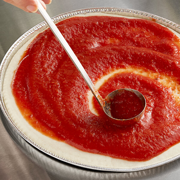 A person using a spoon to spread Conte pizza sauce on a pizza.