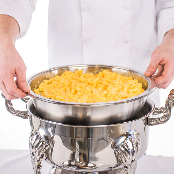 A chef using a Choice Classic round chafer to serve macaroni and cheese.