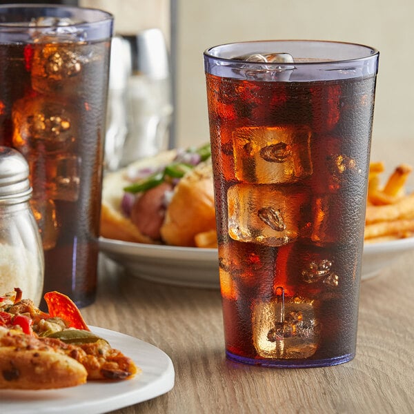 A table with two blue pebbled plastic tumblers filled with ice tea and a plate of food.