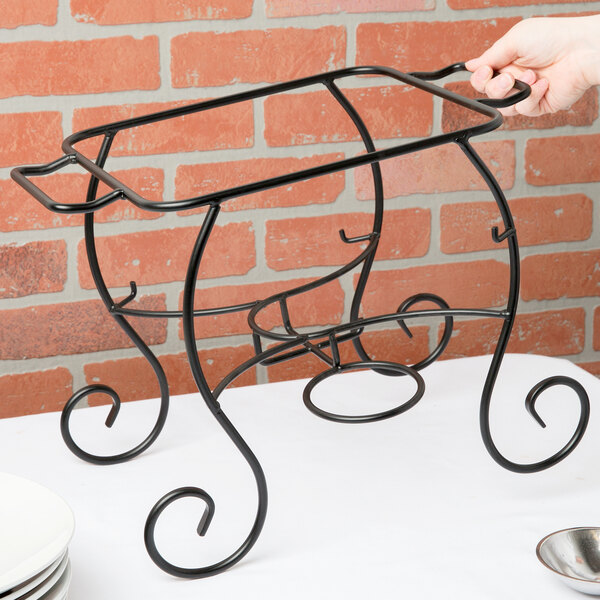 A person using a Choice black wrought iron chafer stand to hold a plate.