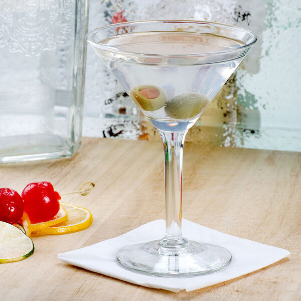 A Libbey cocktail glass with olives on a table.