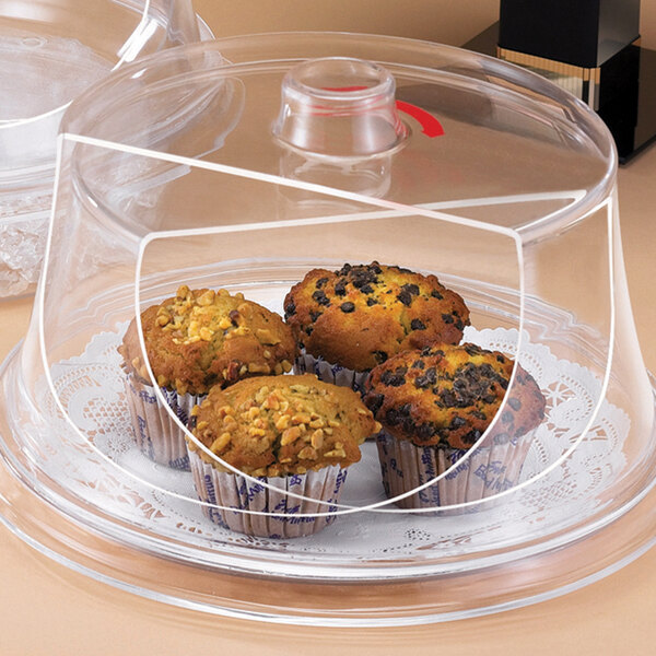 A clear plastic Cal-Mil pastry tray cover on a glass tray with muffins inside.