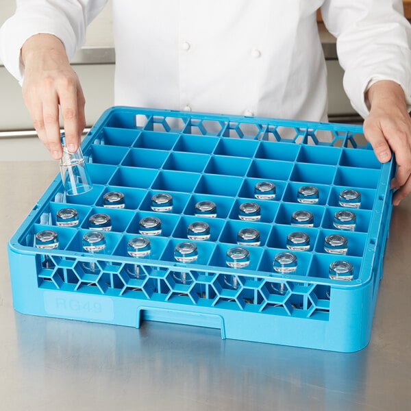 A person holding a blue Carlisle glass rack filled with small bottles.