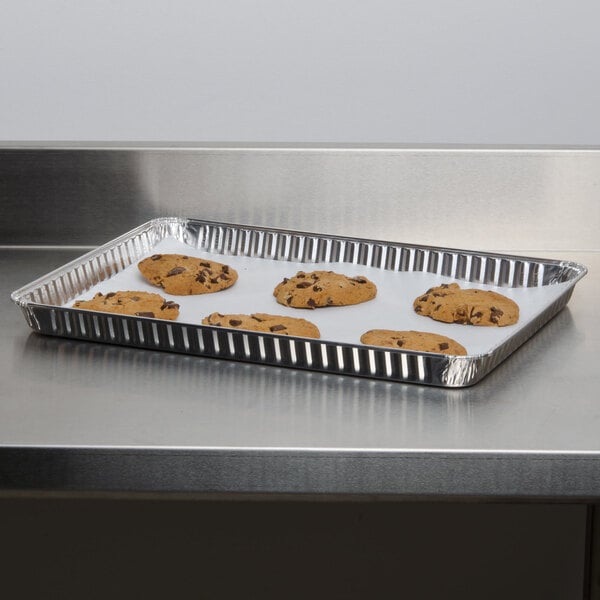 A Durable Packaging 1/2 sheet foil cake pan of cookies on a counter.