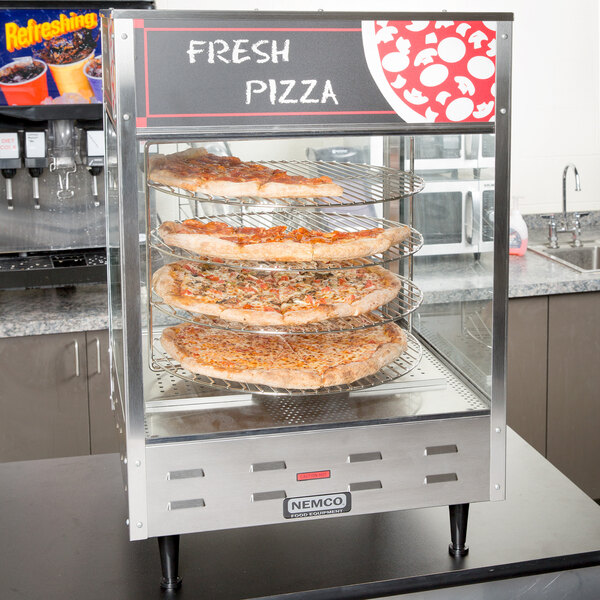 A Nemco pizza merchandiser with pizzas on racks.