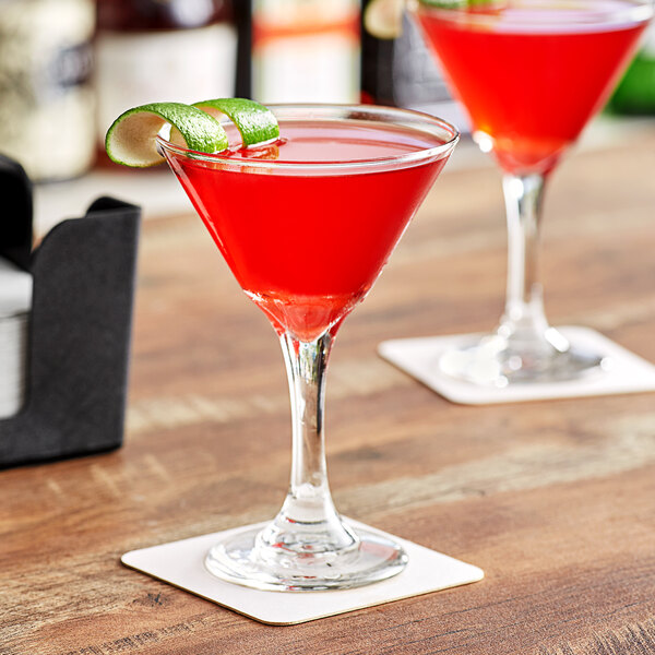 A Acopa martini glass filled with red liquid and a lime wedge on the rim.