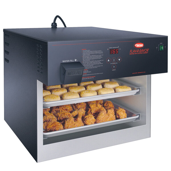 A Hatco Flav-R-Savor heated air curtain with a tray of chicken and biscuits in a school kitchen.