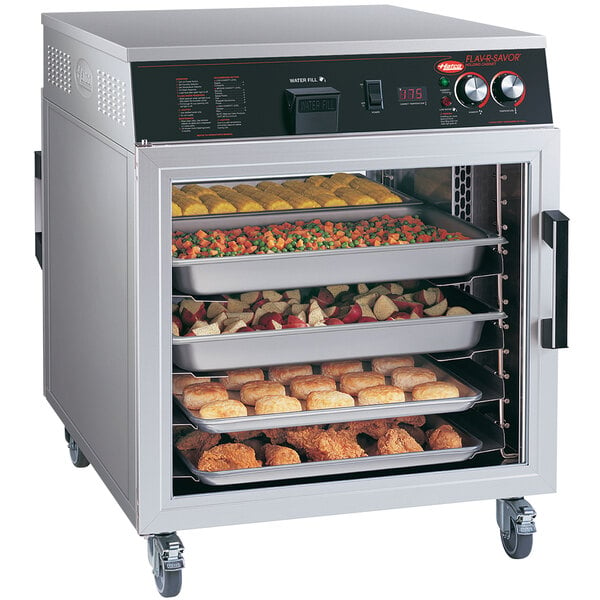 A Hatco Flav-R-Savor holding cabinet with trays of food in an outdoor catering setup.
