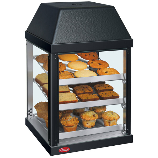 A Hatco countertop display warmer with muffins on shelves.