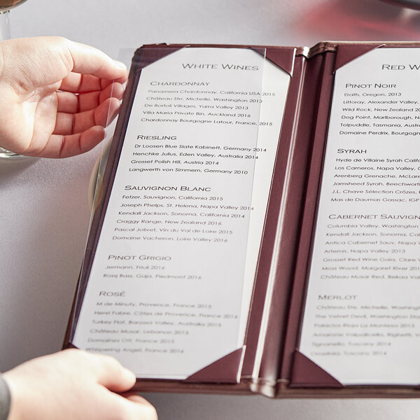 A person holding a menu with wine glasses on it.