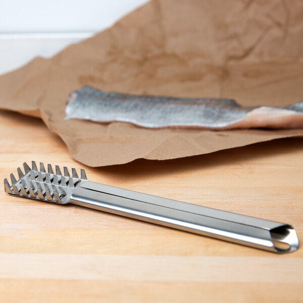 A silver Town stainless steel fish scaler on a wood surface.