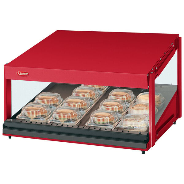 A red Hatco countertop food warmer with food on a slanted shelf.