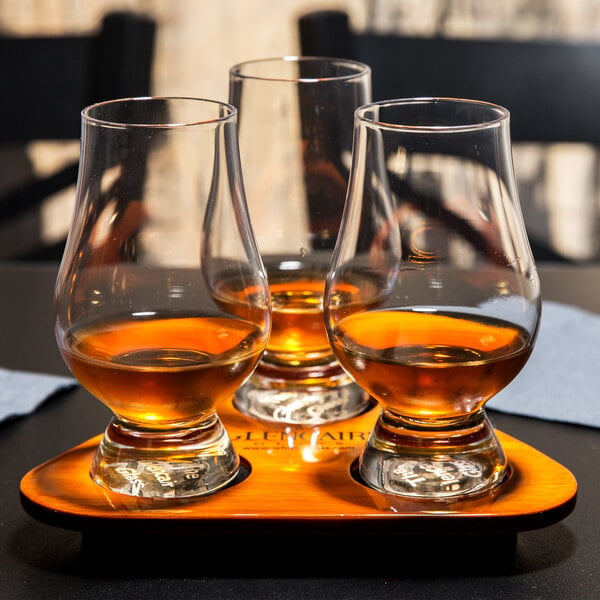 A Stolzle Glencairn Whiskey Tasting Set on a tray with three glasses of whiskey.