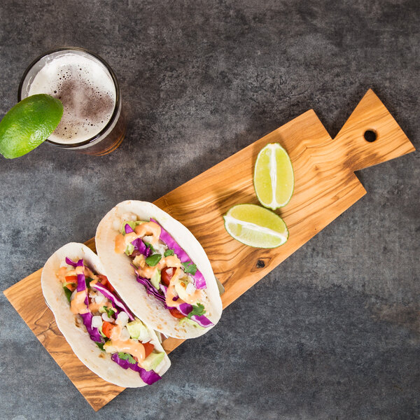 An American Metalcraft olive wood serving board with two tacos, lime wedges, and a glass of beer.