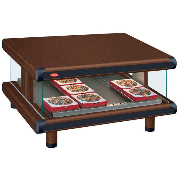 A Hatco countertop food warmer with a slanted shelf holding trays of pizza.