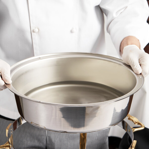 A chef holding a silver Vollrath water pan.