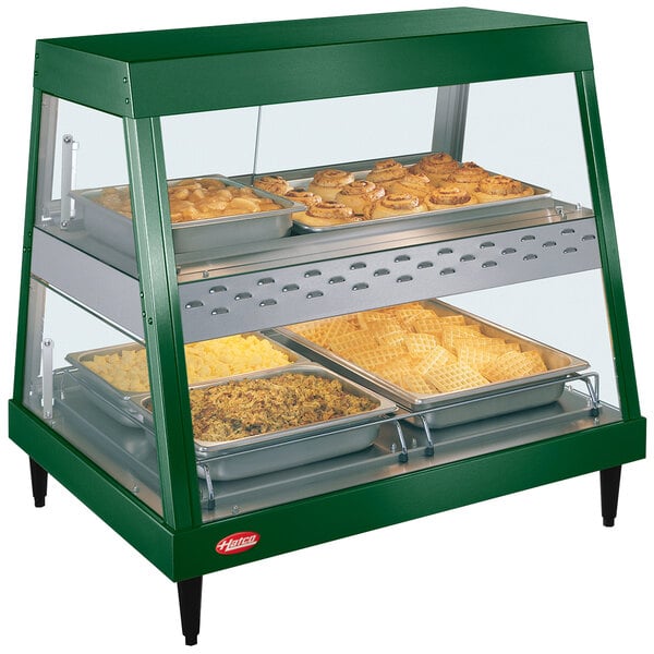 A green Hatco countertop food display case with food on shelves.