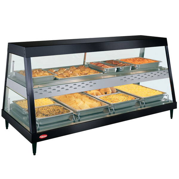 A black Hatco countertop food warmer with trays of food on a counter in a display case.