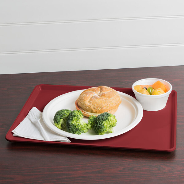 A Cambro cherry red dietary tray with a plate of food, including broccoli.