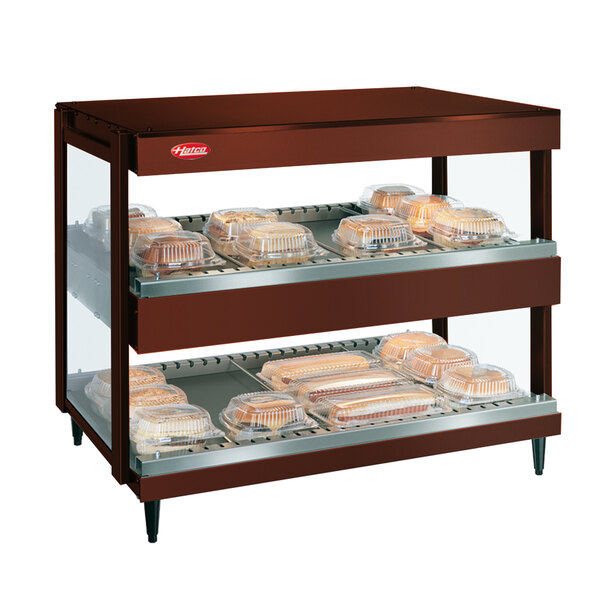 A Hatco Antique Copper countertop double shelf warmer with trays of food.