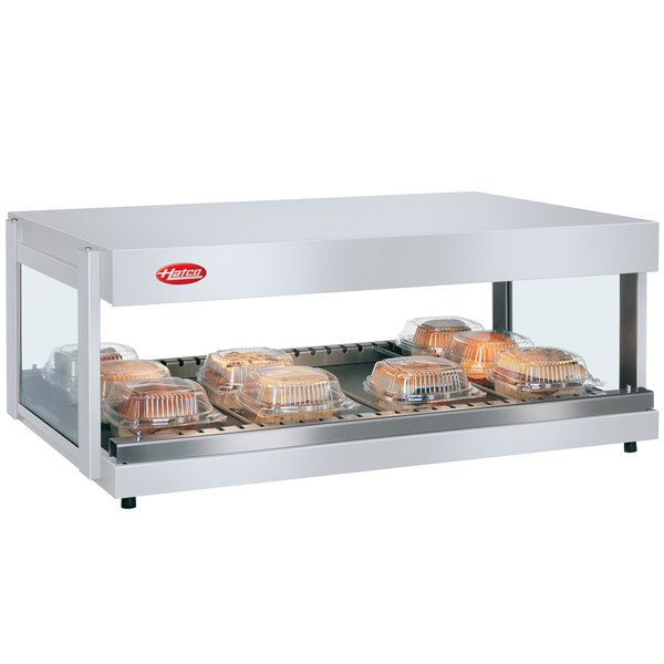 A Hatco countertop food warmer with food trays inside on a counter in a glass case.