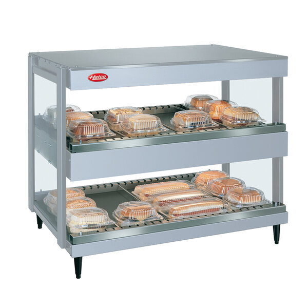 A Hatco White Granite Glo-Ray horizontal double shelf merchandiser with trays of food on shelves.